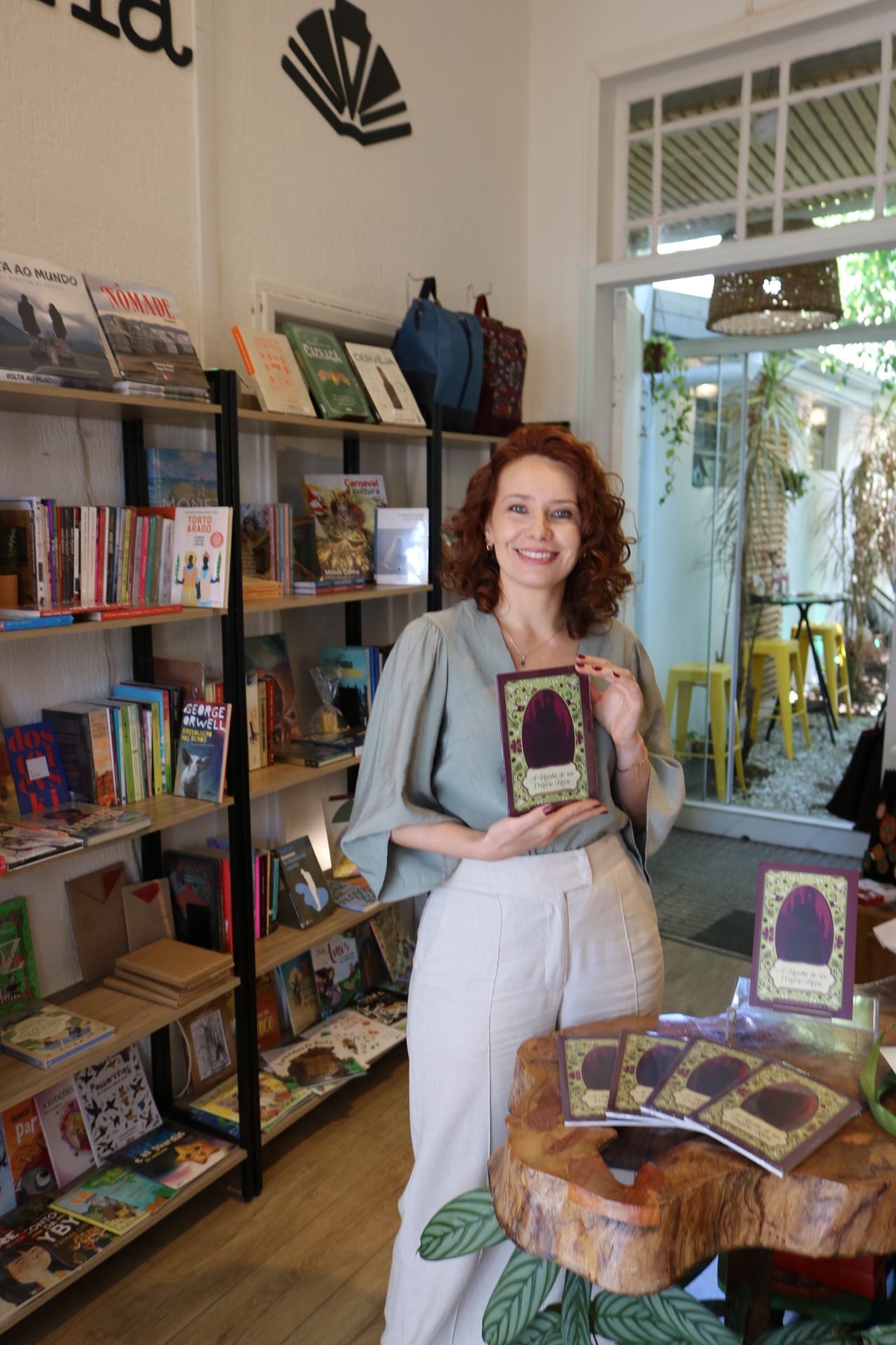 Dayana Barrussi com o livro em uma livraria